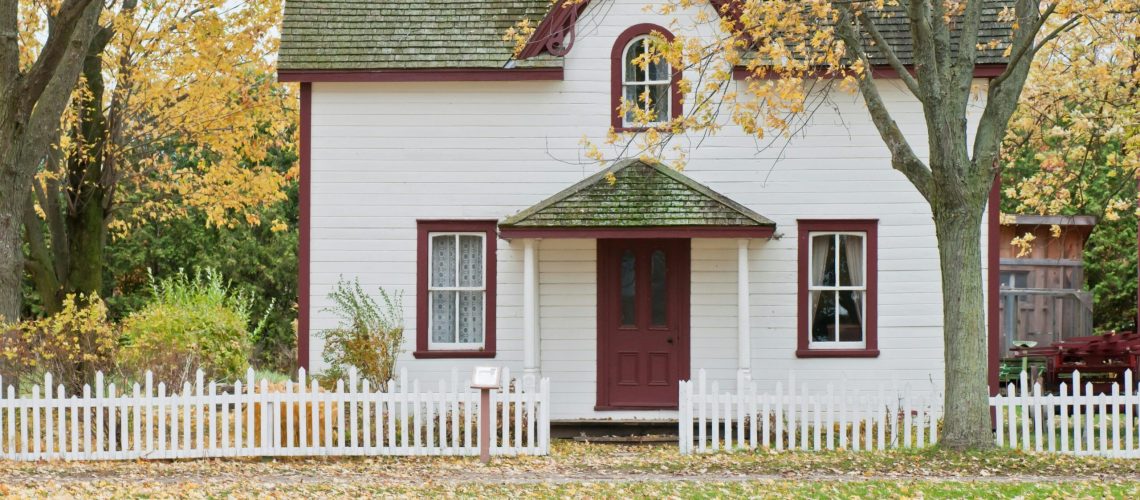 White house with a red door and white picket fence | Foundation Repair | Once and Done Waterproofing | WV, MD, NJ, PA